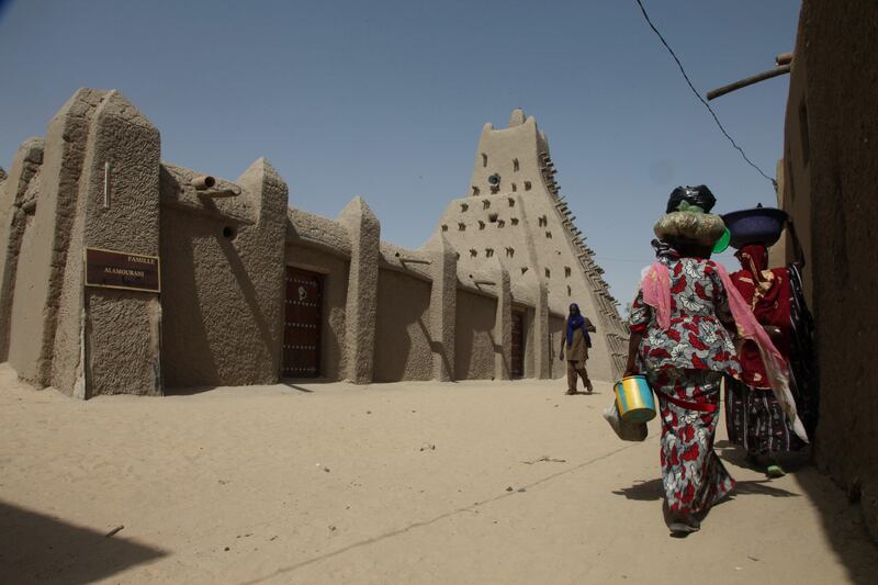 (FILES) This file photo taken on September 19, 2016 in Timbuktu shows women walking near a revered 15th-century mosque which were hacked apart by jihadists in 2012, and restored to their former glory. 
War crimes judges are poised to make legal history on Thursday with a ruling on compensation for the destruction of fabled shrines in the Malian town of Timbuktu, an act ordered by a now-repentant jihadist.
The perpetrator, Ahmad al-Faqi al-Mahdi, was jailed last September for nine years for ordering the 2012 attack on the venerated landmarks.
 / AFP PHOTO / SEBASTIEN RIEUSSEC