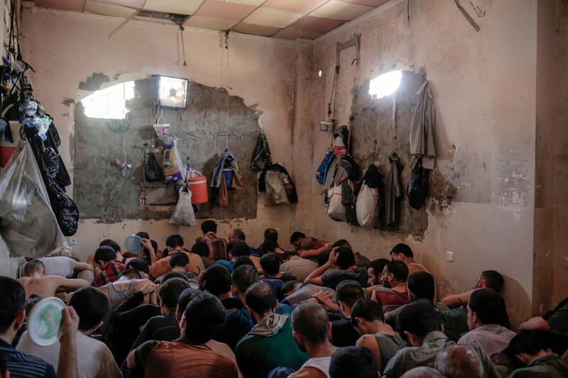 FILE -In this Tuesday, July 18, 2017 file photo, suspected Islamic State members sit inside a small room in a prison south of Mosul. Iraq is holding huge numbers of detainees on suspicion of ties to the Islamic State group _ around 11,000, according to Iraqi officials _ and they are being rushed through counterterrorism courts in trials that raise serious questions over whether justice is being done. At the same time, families are often left in the dark about where their loved ones are being detained or what their fates are. (AP Photo/Bram Janssen, File)