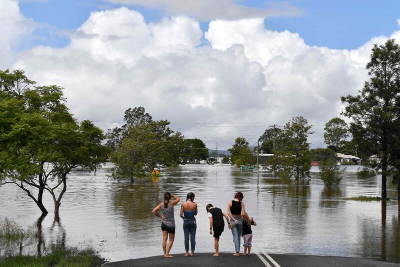 A family surveys a flooded street in Lawrence, 70 kilometres from the New South Wales town of Lismore, Australia. AFP