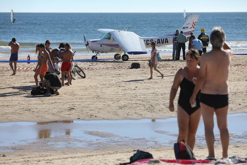 epa06121678 Onlookers watch the recovery of a light plane after two people were killed after the plane made an emergency on Sao Joao beach on Costa de Caparica in Almada, Portugal, 02 August 2017. The victims are a man and a girl eight years old. The two crew members of the plane were unhut and are being questioned by the authorities.  EPA/ANDRE KOSTERS