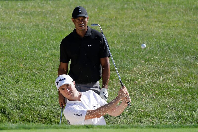 Justin Thomas hits out of a bunker on the 15th hole as Tiger Woods watches during a practice round for the Memorial golf tournament, in Dublin, Ohio. AP Photo