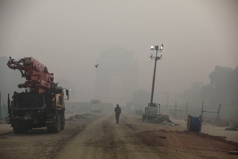 An Indian paramilitary soldier walks near India Gate, which is shrouded in smog. Reuters