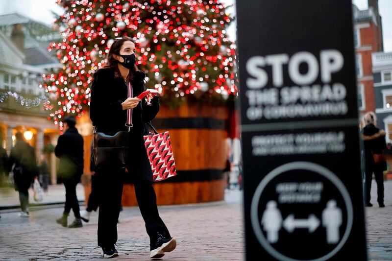 A pedestrian wearing a protective face covering to combat the spread of the coronavirus, walks past the Christmas tree in Covent Garden in central London on November 27, 2020, as life under a second lockdown continues in England.  England will return to a regional tiered system when the national stay-at-home order ends on December 2, and 23.3 million residents in the worst-hit areas are set to enter the "very high" alert level. / AFP / Tolga Akmen
