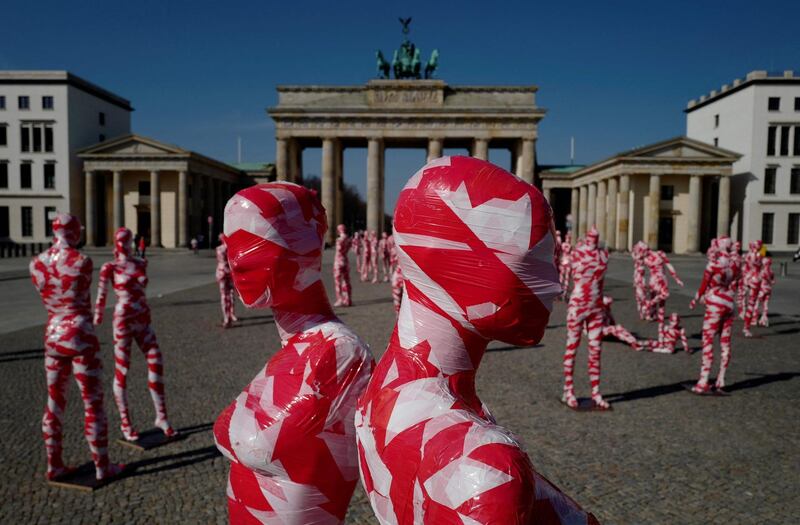 Mannequins wrapped in barrier tape stand in front of Berlin's landmark Brandenburg Gate as part of German artist Dennis Josef Meseg's Corona Memorial called "It is like it is". The moving exhibition will be set up near various landmarks in the German capital over the next days. AFP