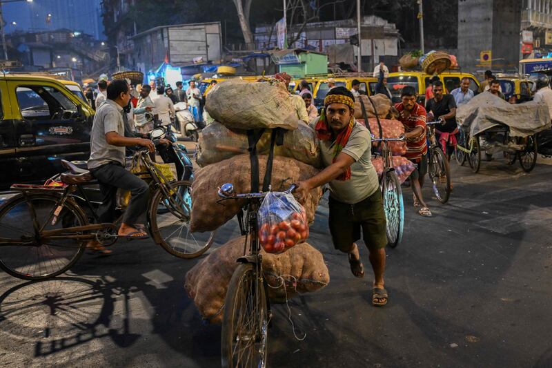 Workers transport sacks of vegetables on their bicycles at a wholesale market in Mumbai. AFP
