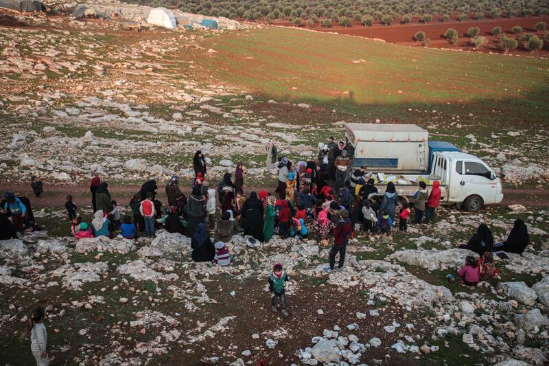 Displaced Syrians from the south of Idlib province receive food aid from a truck in the countryside west of the town of Dana in the northwestern Syrian region.  AFP