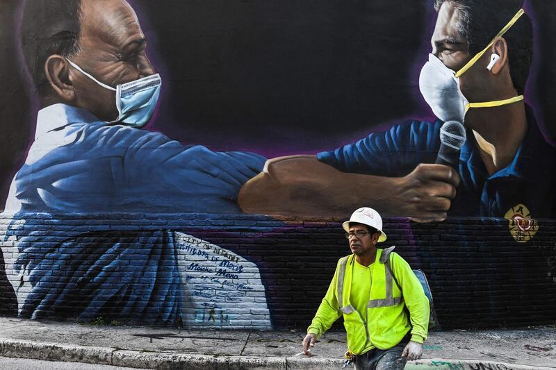 (FILES) In this file photo a construction worker walks past a mural by Hiero Veiga of Moishe Mana (L) and Miami Mayor Francis X. Suarez wearing masks in Wynwood Art District in Miami, Florida on June 29, 2020.  Florida has registered more than 15,000 new cases of coronavirus in a day, easily breaking a record for a US state previously held by California, according to official numbers published on July 12, 2020.The total of 15,299 cases in the hard-hit southeastern state was up sharply, 47 percent above the previous day's total, the Florida state health department reported. 
 - RESTRICTED TO EDITORIAL USE - MANDATORY MENTION OF THE ARTIST UPON PUBLICATION - TO ILLUSTRATE THE EVENT AS SPECIFIED IN THE CAPTION
 / AFP / CHANDAN KHANNA / RESTRICTED TO EDITORIAL USE - MANDATORY MENTION OF THE ARTIST UPON PUBLICATION - TO ILLUSTRATE THE EVENT AS SPECIFIED IN THE CAPTION
