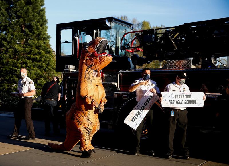 A first responder in a dinosaur costume greets healthcare workers during a shift change along with Bothell firefighters at the Evergreen Health Medical Center,  in Kirkland, Washington, USA. Reuters