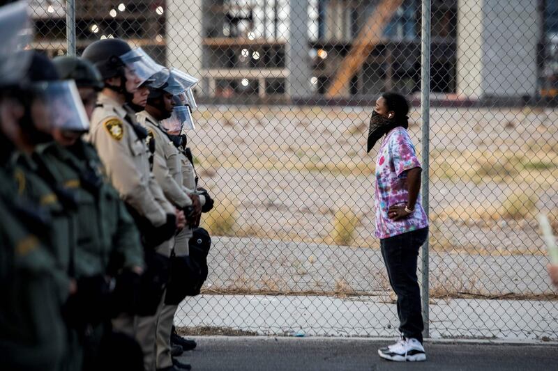 A woman stands in front of Police officers, in downtown Las Vegas, as they take part in a 'Black lives matter' rally in response to the recent death of George Floyd, an unarmed black man who died in police custody.  AFP