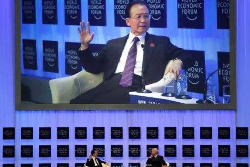 An image of Chinese Premier Wen Jiabao is projected in the background as he sits at left on the stage with Klaus Schwab, founder and executive chairman of the World Economic Forum, during its annual meeting of the New Champions 2010, also known as Summer Davos, in Tianjin, China, Monday, Sept. 13, 2010. Over 1,300 business and government participants from 85 countries are expected at the three-day meeting. (AP Photo/Ng Han Guan) *** Local Caption ***  XHG115_China_Summer_Davos.jpg