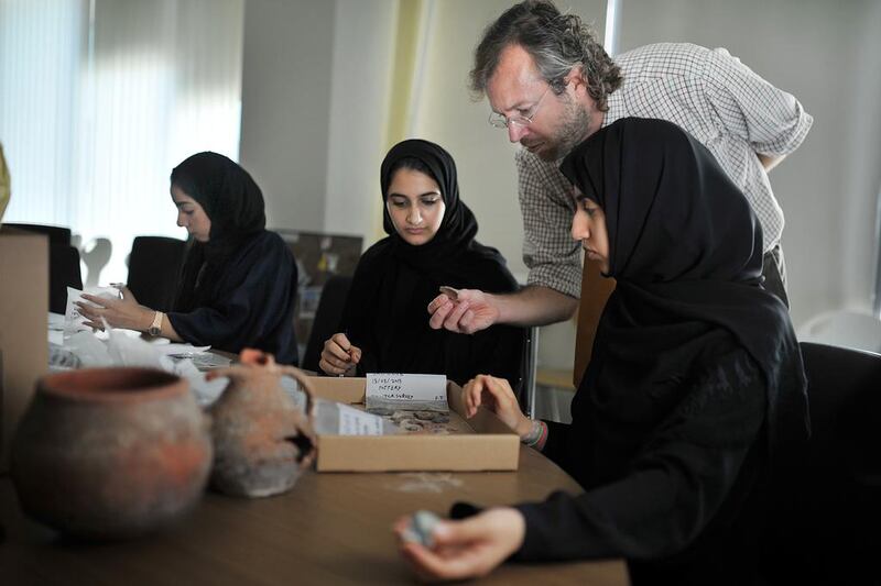 Dunia Al Blooshi, left, Afra Al Nuaimi and Shamsa Al Dhaheri assess pottery finds from Saadiyat in their Emirati Studies class at Zayed University under the tutelage of Dr Timothy Power, an archaeologist and assistant professor at the university. Delores Johnson / The National