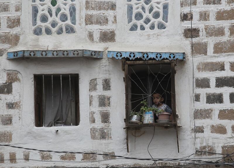 A Yemeni child peers out of a window with a wire fence at a historic building in the old quarter of Sana'a, Yemen. EPA