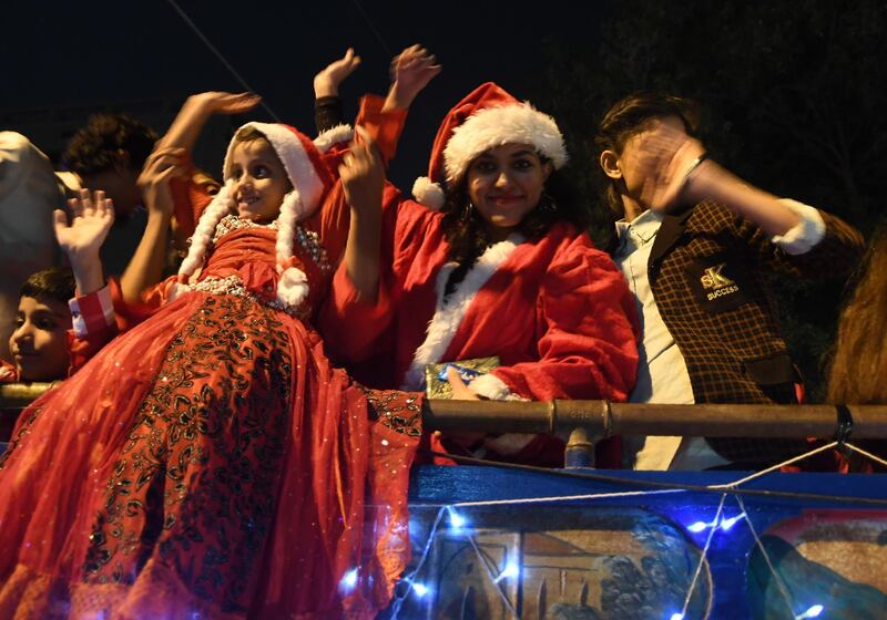 Girls wearing Santa costumes wave from a bus on a street in Karachi, as part of the Christmas celebrations.  AFP