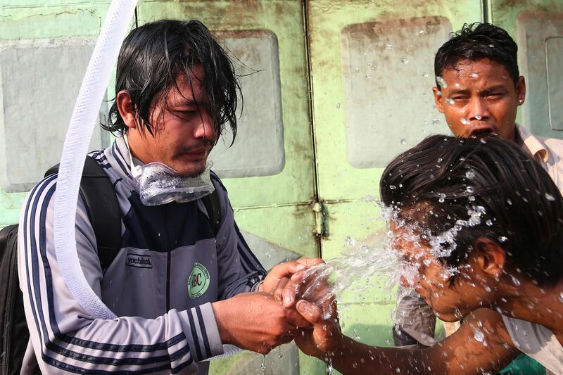 People rinse their faces with water after tear gas was used to disperse a protest in Mandalay, Myanmar. AP