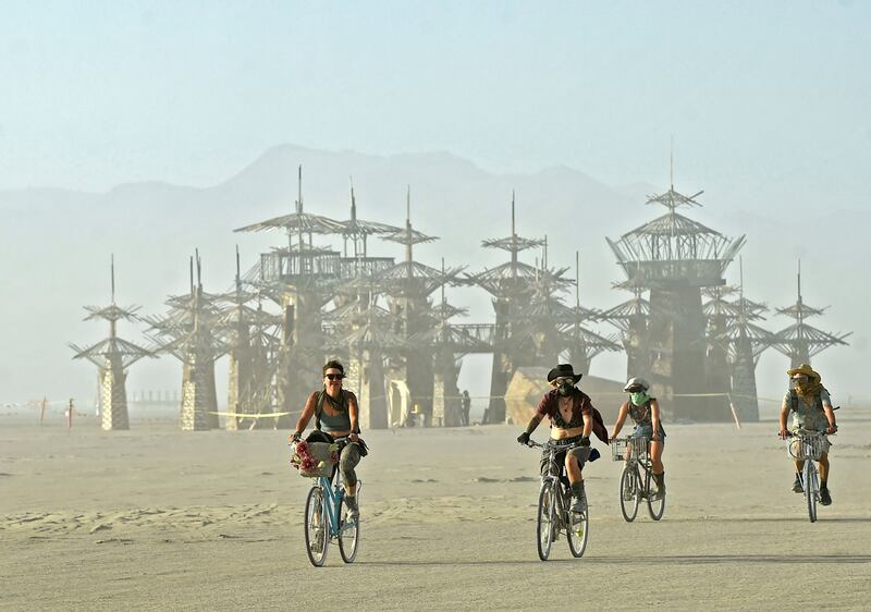 A group of festivalgoers ride their bikes on a dusty afternoon in Nevada's Black Rock Desert during Burning Man.  