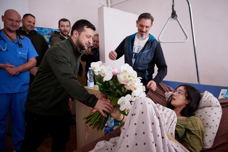 President Volodymyr Zelenskiy presents flowers to Kateryna Vlasenko, 16 - who was injured as she fled with her family from the town of Vorzel - at a hospital in Kyiv. Reuters
