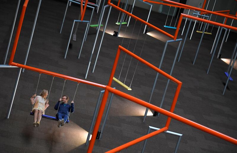 Two visitors ride on swings which form part of the new installation 'One Two Three Swing!' by Danish art collective SUPERFLEX, at the Tate Modern in London. Toby Melville / Reuters