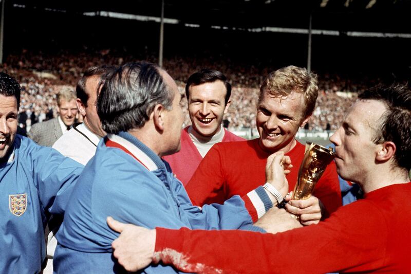 Nobby Stiles kisses the World Cup trophy as Bobby Moore is congratulated by manager Alf Ramsey. PA