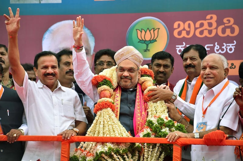 President of Bharatiya Janatha Party (BJP) Amit Shah (C) waves along with senior party leaders former Chief Ministers of Karnataka, D.V. Sadananda Gowda (L) and B. S. Yediyurappa (R) during a reception function held during Shah's arrival in Bangalore on August 12, 2017. / AFP PHOTO / STR