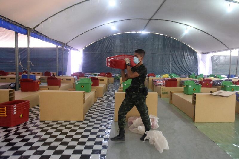 A soldier carries lids for containers to be used by patients next to newly set up cardboard beds at a field hospital in Pattani, as Thailand seeks to contain a surge in Covid-19 coronvirus cases.  AFP