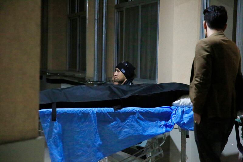 Afghan men sit near the body of a relative at a hospital in Kabul after a suicide bombing.  AP