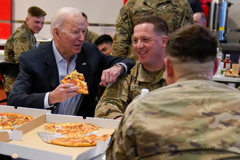 Mr Biden eats pizza as he talks to members of the 82nd Airborne Division at the G2A Arena in Jasionka, Poland.  AP