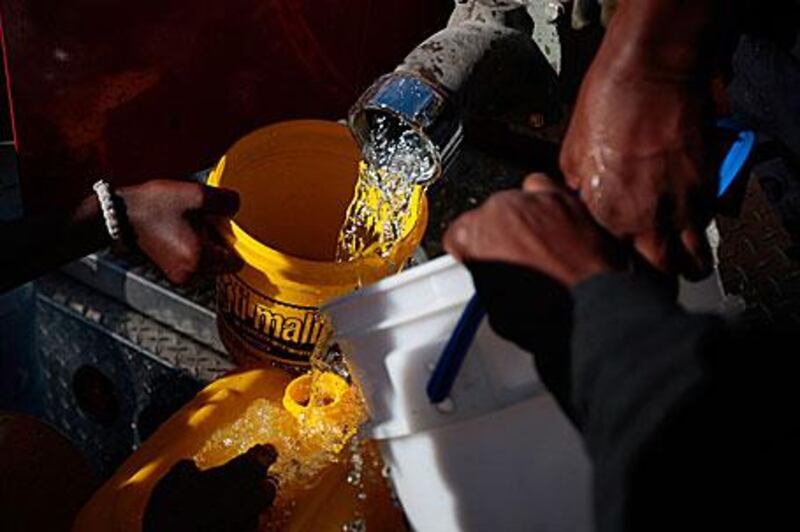 People hold out buckets for water distributed from a fire engine in Port-au-Prince yesterday.