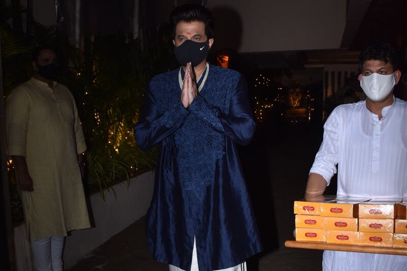 Father of the bride Anil Kapoor distributing sweets to photographers after the wedding.