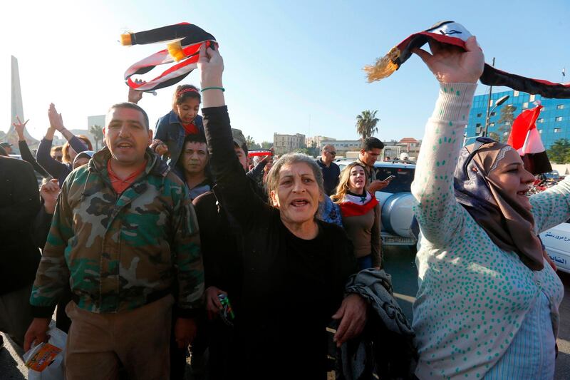 Syrians wave the national flag as they gather at the Umayyad Square in Damascus, to condemn the strikes carried out by the US, Britain and France against the Syrian regime. Louai Beshara / AFP