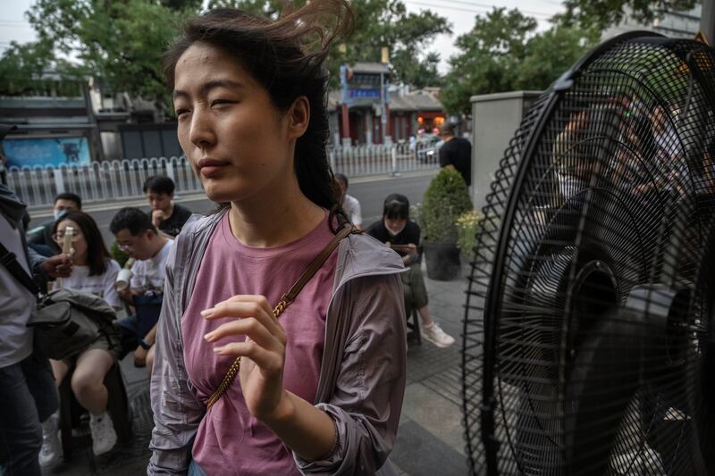 A woman cools herself down with a fan in Beijing