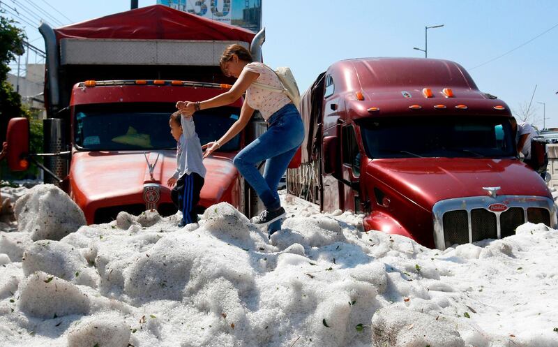 A woman and a child walk on hail in the eastern area of Guadalajara, Mexico. AFP