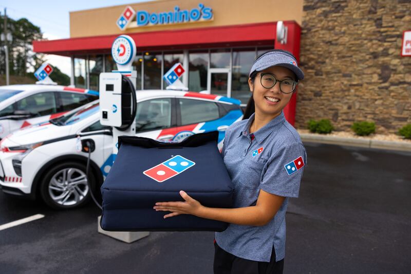A Domino's worker prepares to get into a Chevy Bolt.
