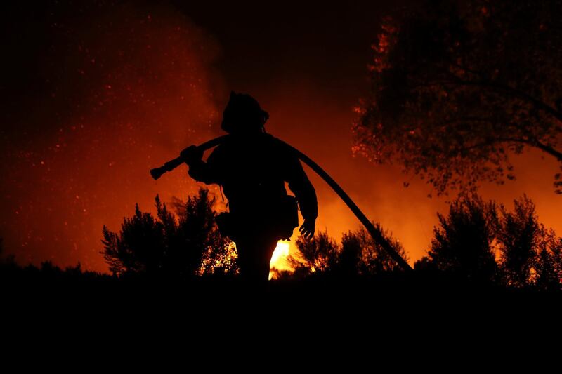 A firefighter works at the top of a hill. Mike Blake / Reuters