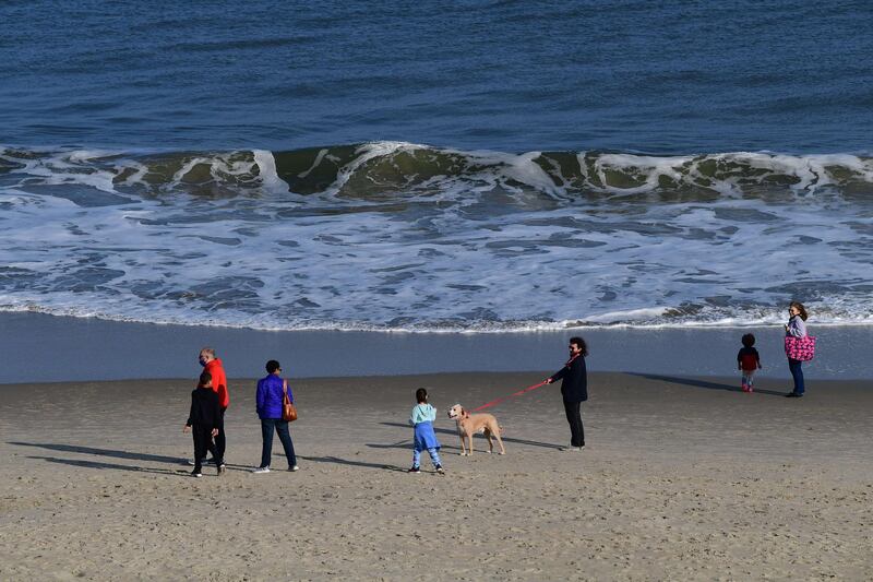 A girl greets a dog by the ocean in Rehoboth Beach, Delaware. Due to the coronavirus pandemic, face masks are required on the boardwalk and strongly recommended on the beach. AFP