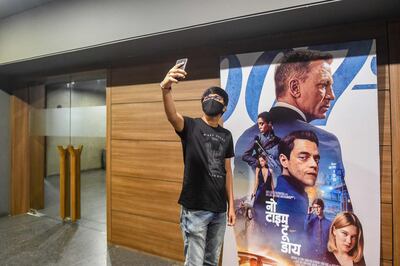 A fan takes a selfie with his mobile phone next to a poster of James Bond movie 'No Time to Die' at a cinema in Ahmedabad. Surging demand for electronics during the pandemic has contributed to the global shortage of semiconductors. Photo: AFP