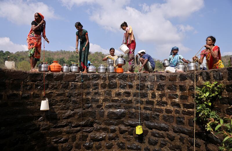 Women lower plastic containers on ropes to draw water from a well in Telamwadi, near Mumbai. Reuters