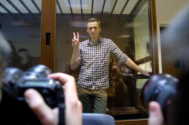 Russian opposition leader Alexei Navalny gestures posing for photographers as he stands in a cage in the Babuskinsky District Court in Moscow, Russia, Saturday, Feb. 20, 2021. A Moscow court has rejected Russian opposition leader Alexei Navalny's appeal against his prison sentence. Earlier this month, a lower court sentenced Navalny to two years and eight months in prison for violating terms of his probation while recuperating in Germany from a nerve agent poisoning that he blames on the Kremlin. (AP Photo/Alexander Zemlianichenko)