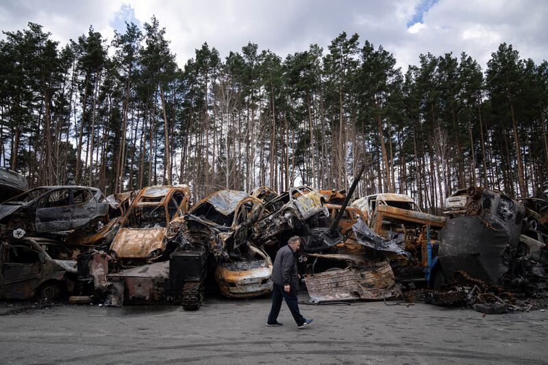 A man walks past a storage place for burned armed vehicles and cars, on the outskirts of Kyiv. AP