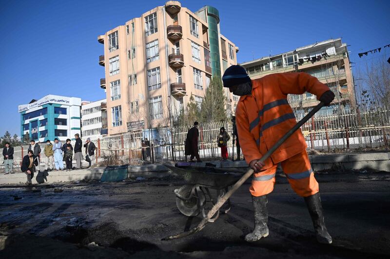 Residents watch a municipal worker clear a street after multiple rockets were fired in Kabul on December 12, 2020 in the second such attack on the Afghan capital in less than a month.  AFP
