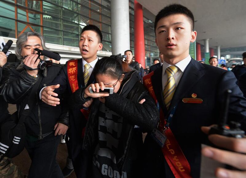 A crying woman is escorted to a bus for relatives at the Beijing Airport after news of the missing Malaysia Airlines Boeing 777-200 plane on March 8, 2014.  Malaysia Airlines said a flight carrying 239 people from Kuala Lumpur to Beijing went missing early on March 8, and the airline was notifying next of kin in a sign it expected the worst. AFP PHOTO/Mark RALSTON

