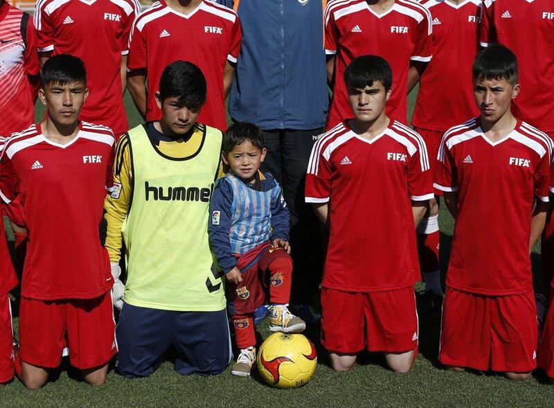 Five year-old Murtaza Ahmadi (C) wears a shirt of Barcelona's star Lionel Messi as he poses with members of a youth soccer team at the Afghan Football Federation headquarters in Kabul, Afghanistan February 2, 2016. Barcelona star Lionel Messi will meet an Afghan boy who gained Internet fame after a touching series of photographs went viral, showing him playing in a shirt improvised from a plastic bag and bearing the name and playing number of his hero. REUTERS/Omar Sobhani