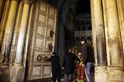 Christian clerics open the doors of the Church of the Holy Sepulchre, traditionally believed by many Christians to be the site of the crucifixion and burial of Jesus Christ, in Jerusalem, Wednesday, Feb. 28, 2018. Christian leaders said Tuesday that they will reopen the Church of the Holy Sepulchre in Jerusalem after Israeli officials suspended a plan to impose taxes on church properties in the holy city. (AP Photo/Mahmoud Illean)