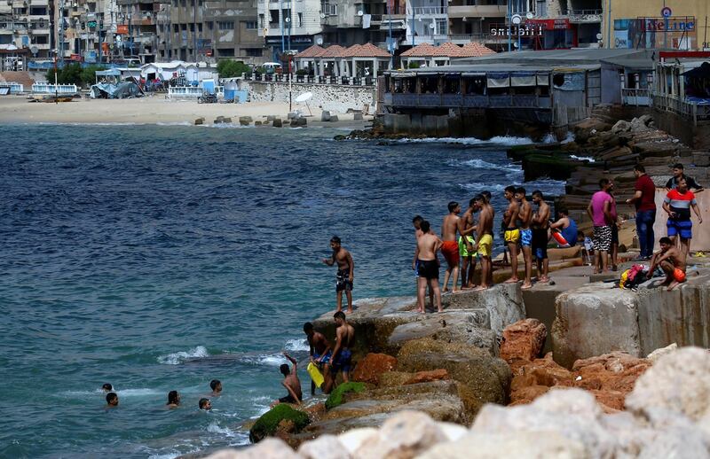 A youth group of people swim and stand on the rocks during summer vacation at the Mediterranean Sea in Alexandria. Reuters