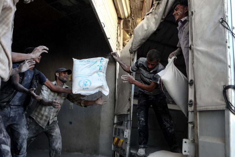 epaselect epa06117910 Workers empty an aid truck, at rebel-controlled Al-Nashabiyah, outskirts of Damascus, Syria, 30 July 2017. Relief convoys entered Al-Nashabiyah city from WFP, UNICEF, UNFPA, UNHCR, and SARC, it's the first time that convoys enter to this area from the bigining of the Syrian crisis.  EPA/MOHAMMED BADRA