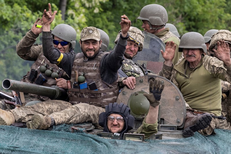 Defiant Ukrainian service members ride on top of a military vehicle, amid Russia's invasion of Ukraine, on the road connecting Kostiantynivka and Bakhmut, in Donetsk region. Reuters