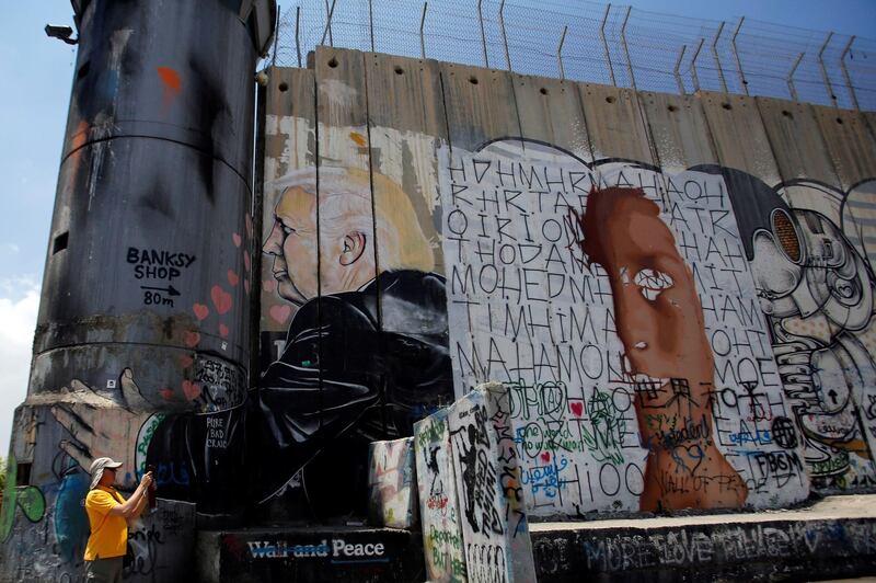 A man takes pictures near the Israeli barrier with a mural depicting US President Donald Trump in Bethlehem, Israeli-occupied West Bank. Reuters