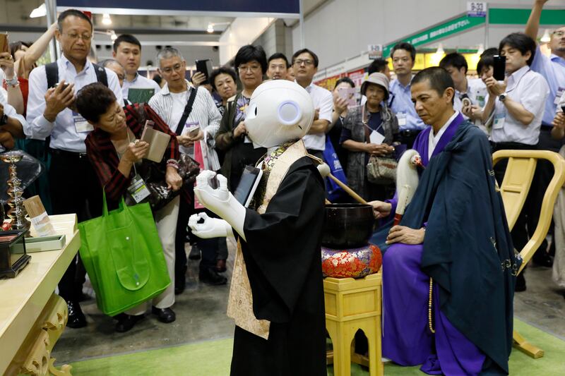 Pepper, a robot developed by SoftBank Corp, takes a part in a demonstration of funeral ceremony with a Buddhist priest at the Tokyo International Funeral and Cemetery Show.  Kimimasa Mayama / EPA