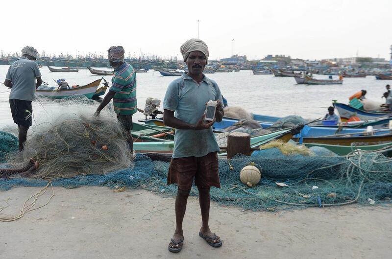 (FILES) In this file photo taken on November 9, 2018 Indian fisherman Satish, 40, poses with his smartphone -- wrapped in plastic to keep it dry -- at Kasimedu harbour in Chennai. / AFP / ARUN SANKAR
