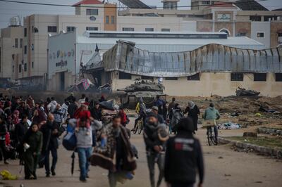 Internally displaced Palestinians walk past Israeli tanks in Gaza. EPA