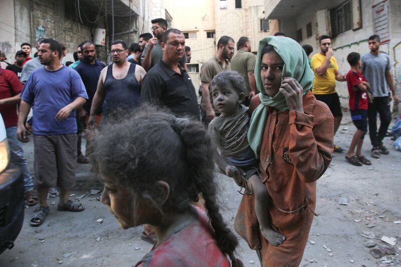 A Palestinian woman, covered in dust, carries a child in Gaza city. AFP